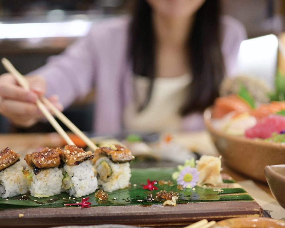 Young asian women eating delicious Unagi Sushi with chopsticks at restaurant - Viking Travel