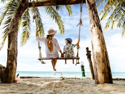 Mother and son enjoying summer day while on swing at beach - Viking Travel