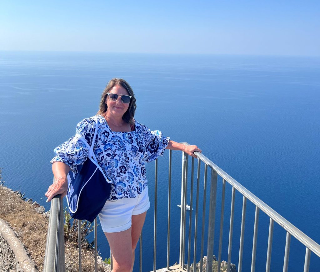 Mary Ann standing on a platform overlooking the Mediterranean Sea - Viking Travel 