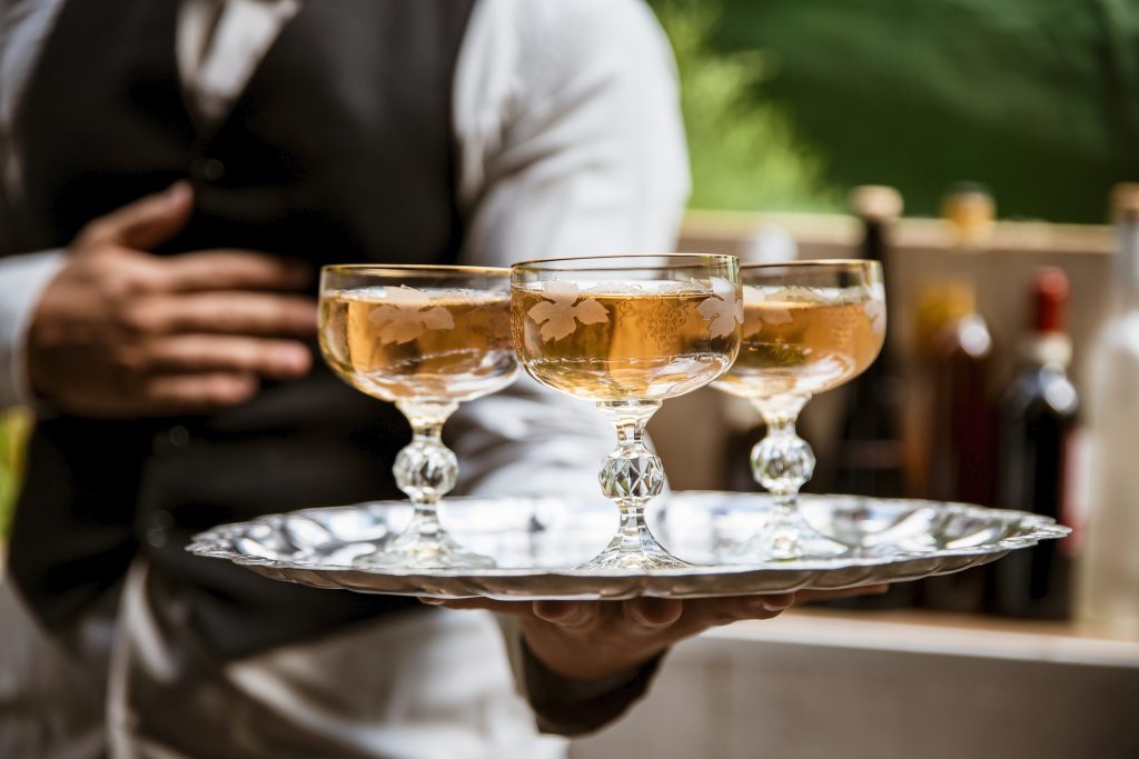 Professional waiter holding a tray with white wine in elegant crystal glasses on Caribbean cruise - Viking Travel