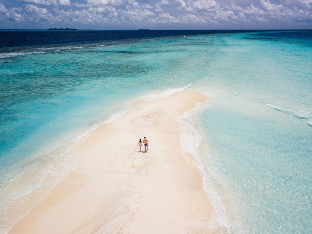 Young adult couple standing on a sandbank against turquoise water in Maldives - Viking Travel