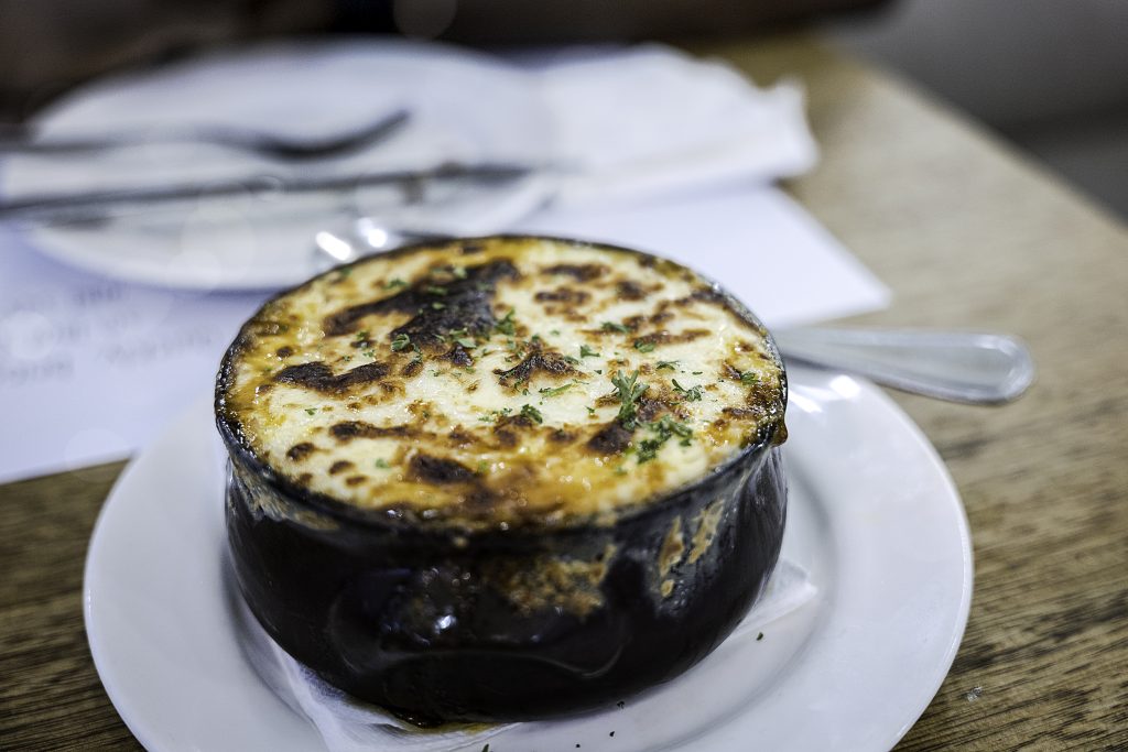 Moussaka, a very typical Greek dish served in a black bowl - Viking Travel