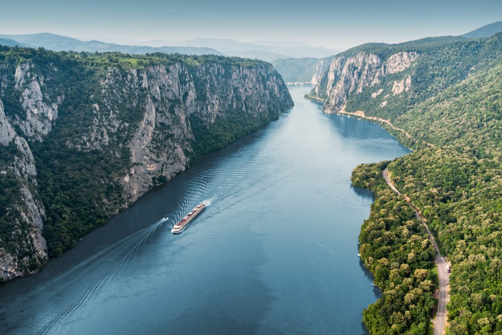 Aerial view of a cruise ship traveling through the Danube River's Iron Gate between Serbia and Romania - Viking Travel